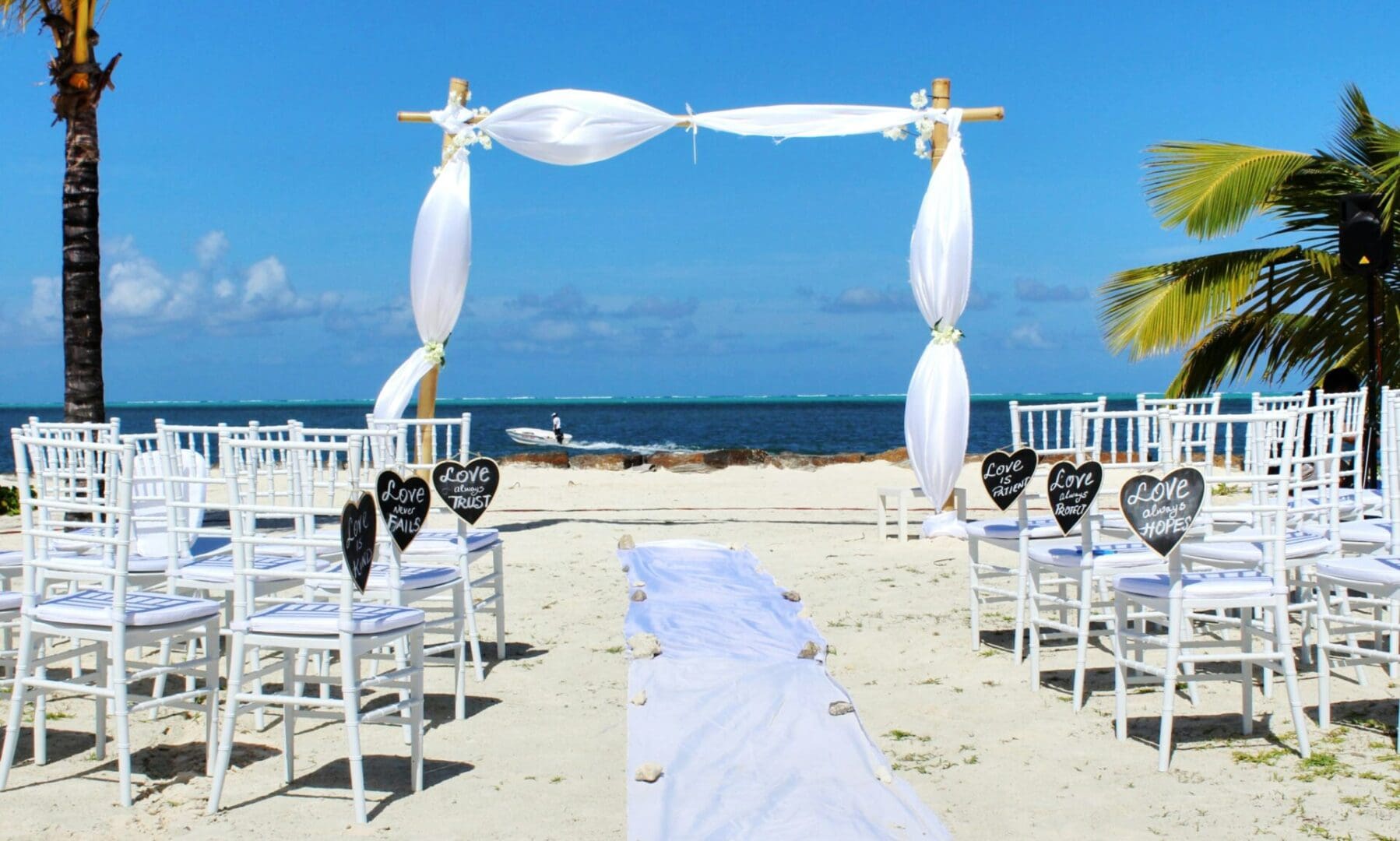 A beach wedding with white chairs and a blue sky