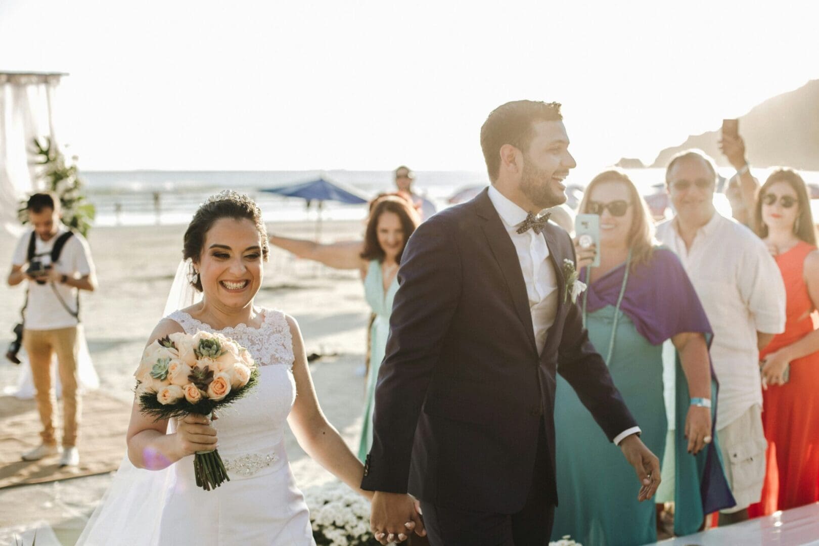 A bride and groom walking down the beach